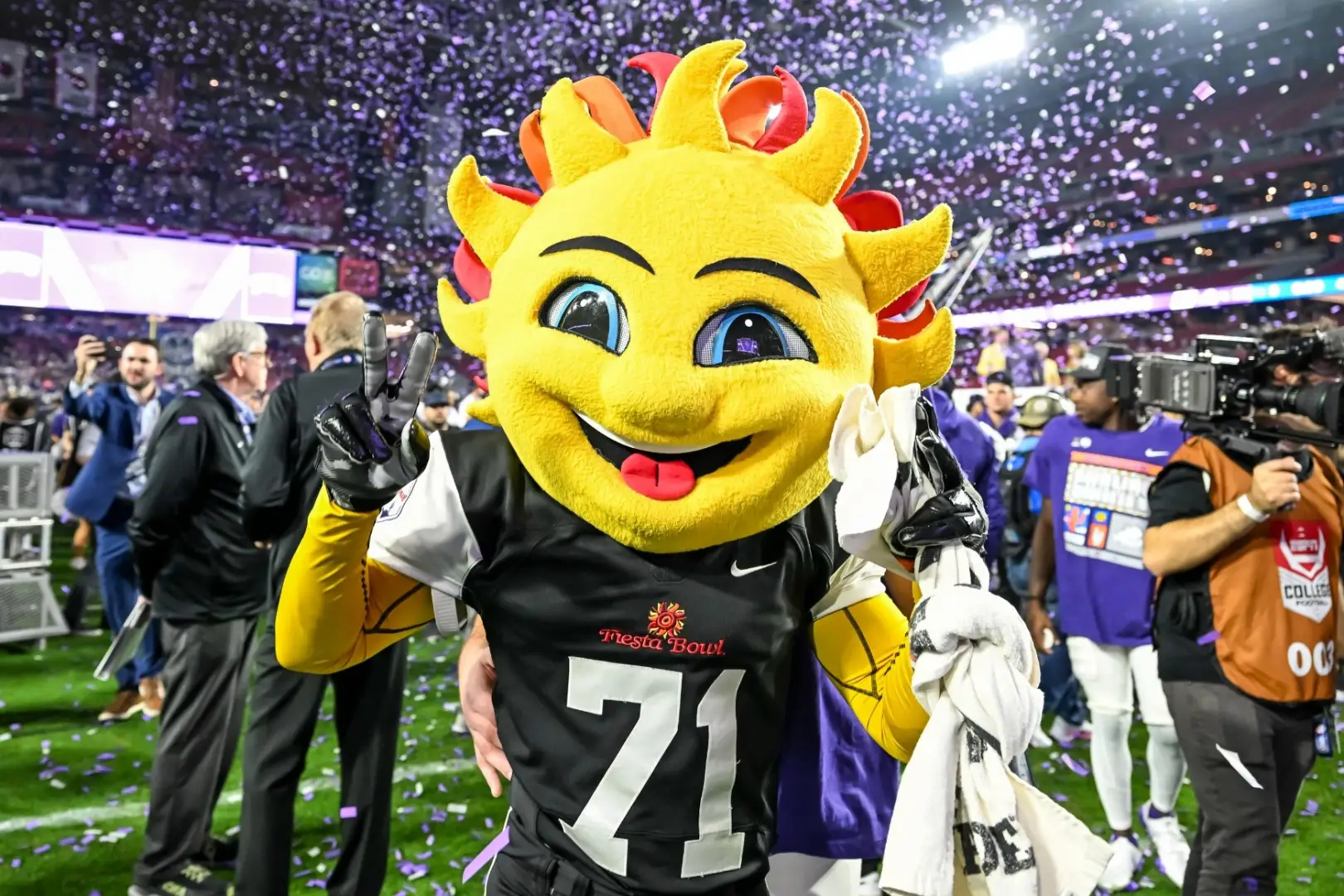 A person in a sun mascot costume on the field